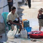 Criança coleta água em um campo de refugiados em Gaza.