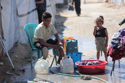 Criança coleta água em um campo de refugiados em Gaza.