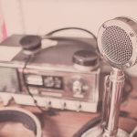 Microfone vintage e aparelho de rádio com fones de ouvido sobre uma mesa de madeira