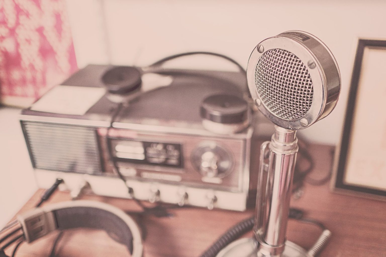 Microfone vintage e aparelho de rádio com fones de ouvido sobre uma mesa de madeira