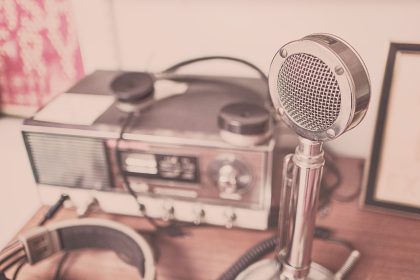 Microfone vintage e aparelho de rádio com fones de ouvido sobre uma mesa de madeira